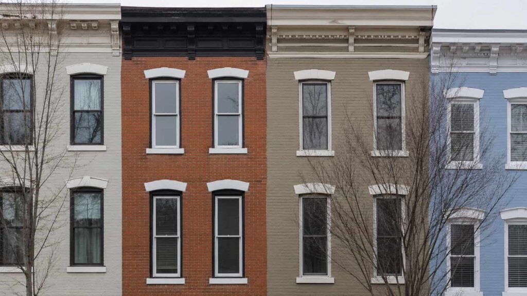 Row of attached townhouse facades with tall sash windows