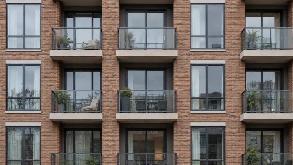 Apartment building facade with repeating window openings and sliding balcony doors